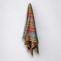 A Buchanan clan tartan blanket with fringing, hanging against a white background.