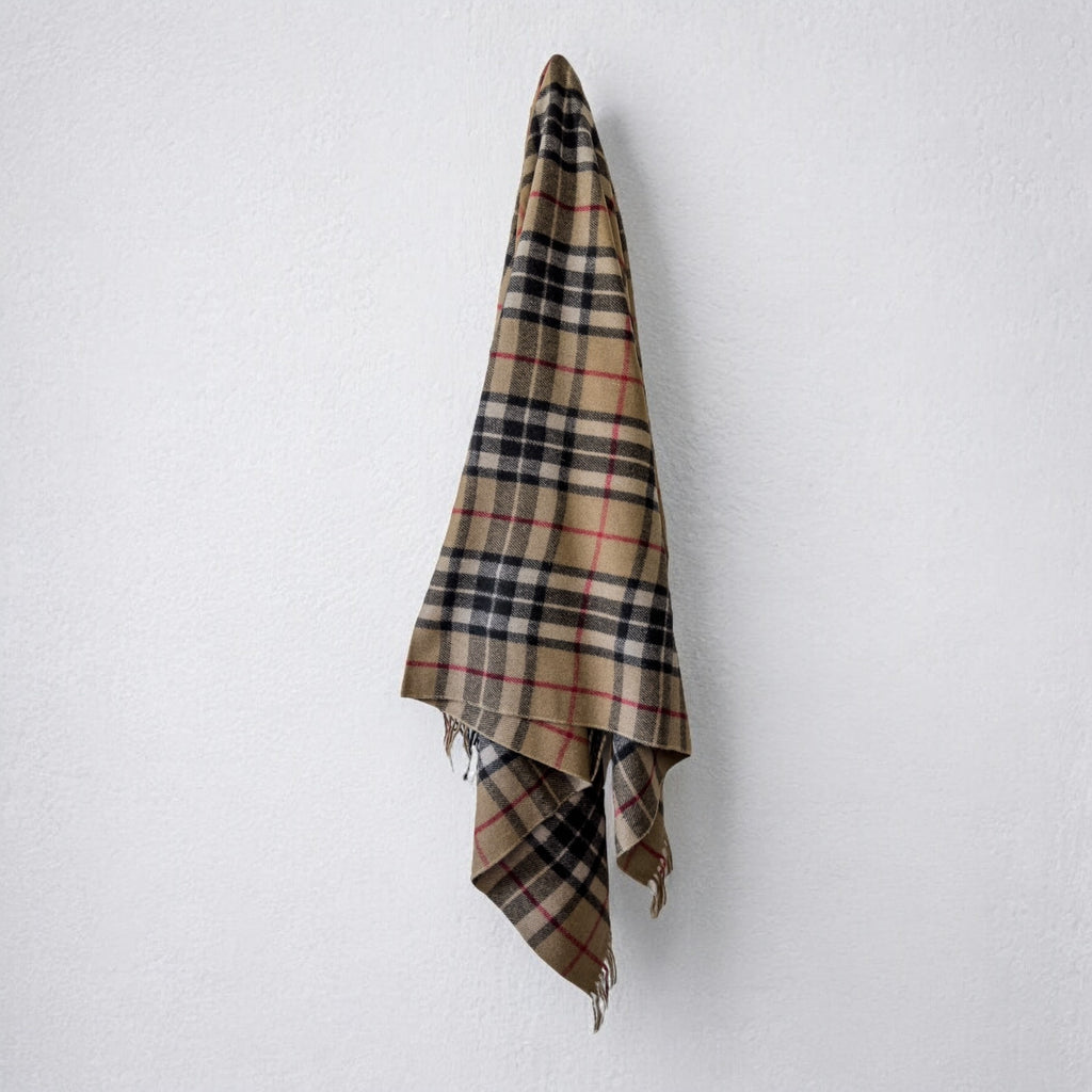 a 100% recycled blanket in camel thomson tartan hanging from a wall hook on a white background