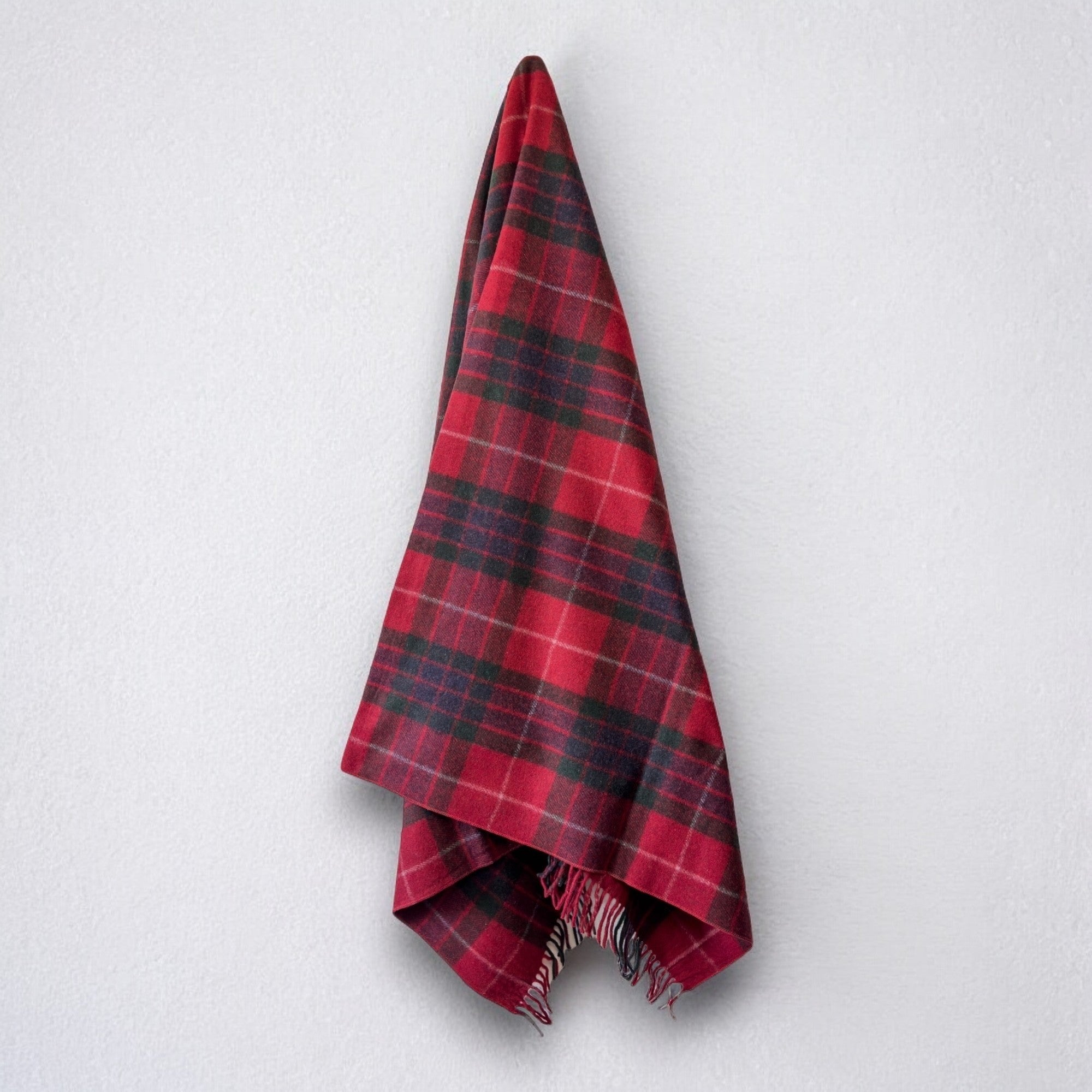 a 100% recycled blanket in fraser red tartan hanging from a wall hook on a white background 