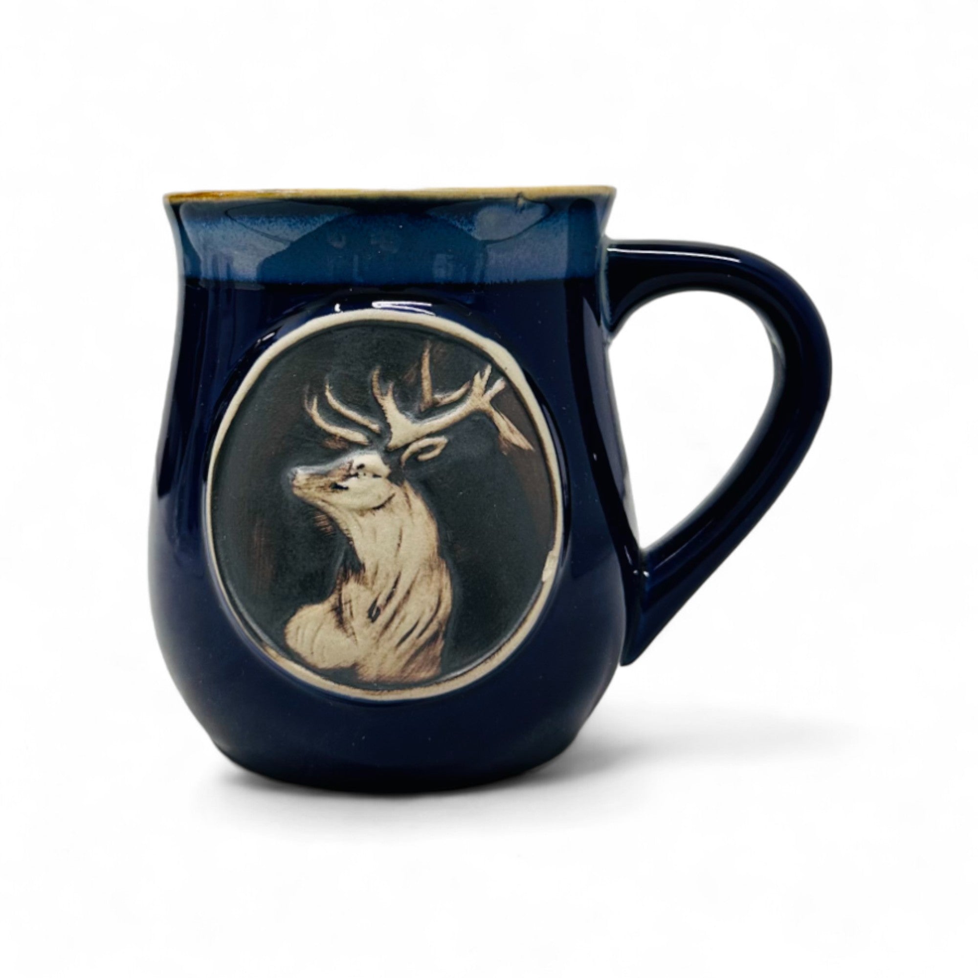A blue stoneware mug with a white stag head design, fired at high temperatures with a sleek blue enamel finish.