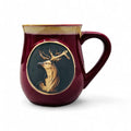 A red stoneware mug with a detailed stag head design in the center.