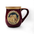 A red stoneware mug with a detailed Edinburgh Castle design in the center.