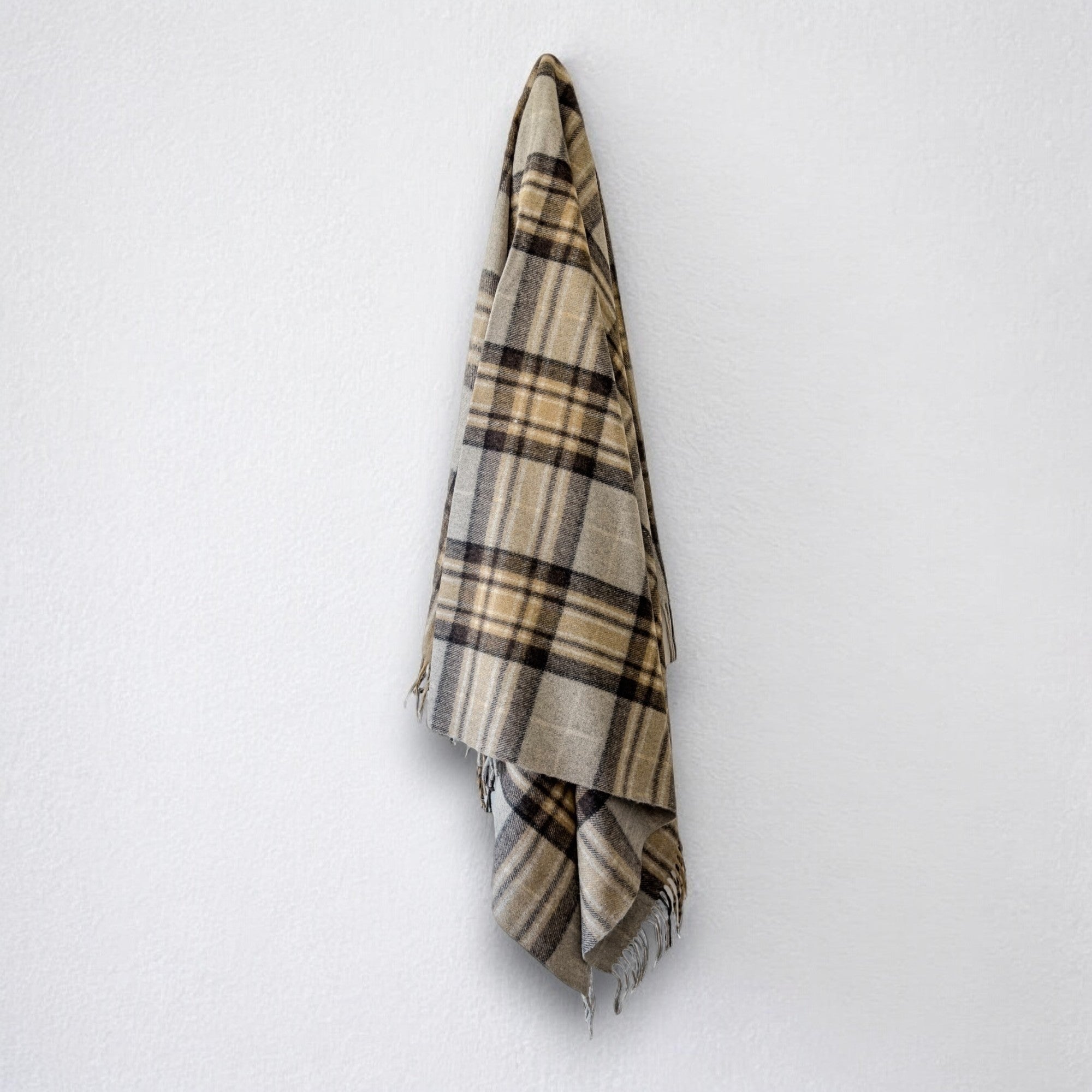 a 100% recycled blanket in mackellar tartan hanging from a wall hook on a white background 