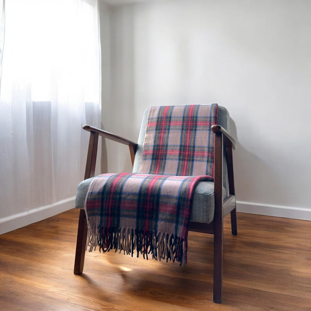 a 100% recycled blanket in stewart dress tartan draped over a chair in a cosy room