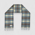A Stewart Muted Blue tartan scarf made of 100% lambswool, displayed flat with fringes, showing the pattern of blue, grey, and white checkers.