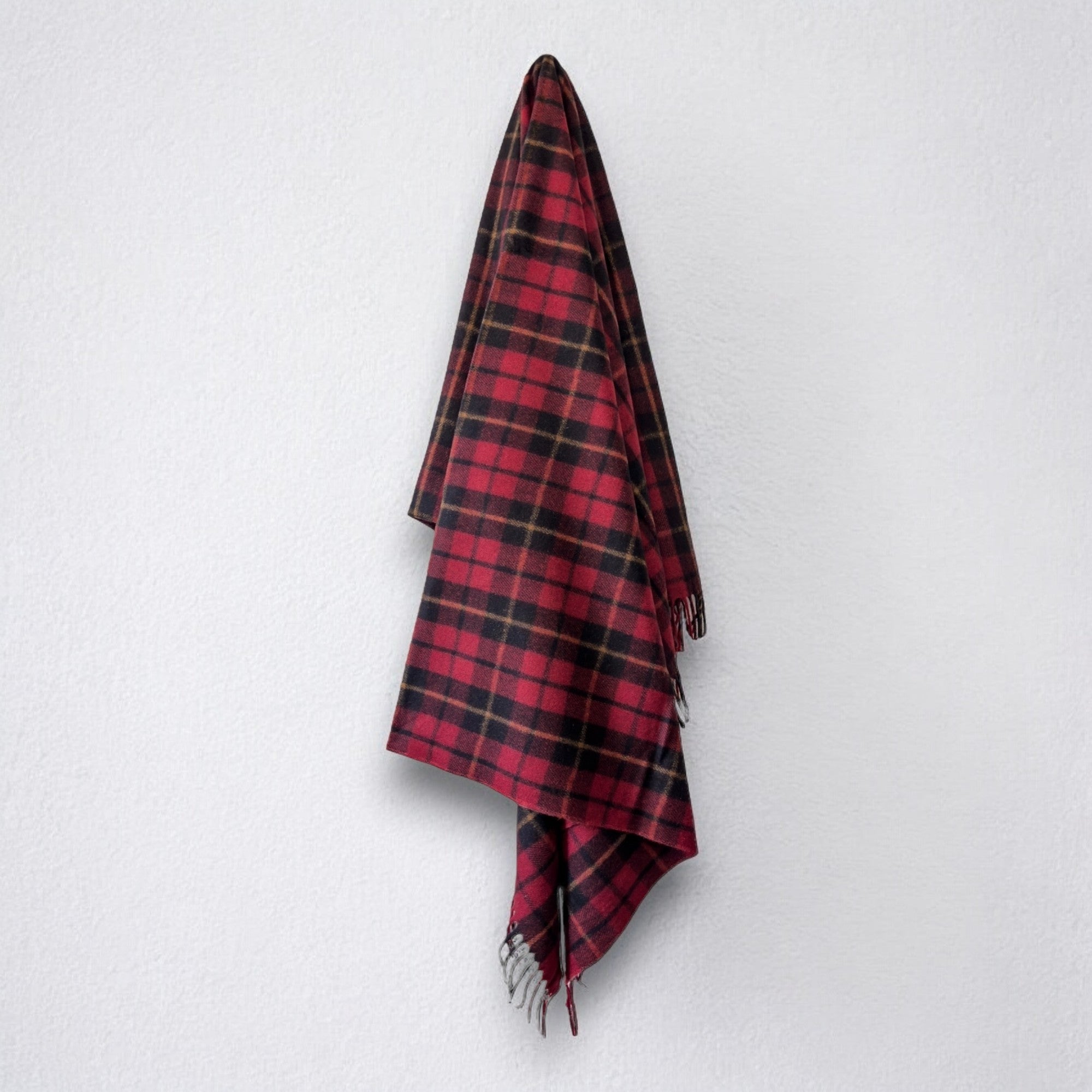 a 100% recycled blanket in wallace tartan hanging from a wall hook on a white background 