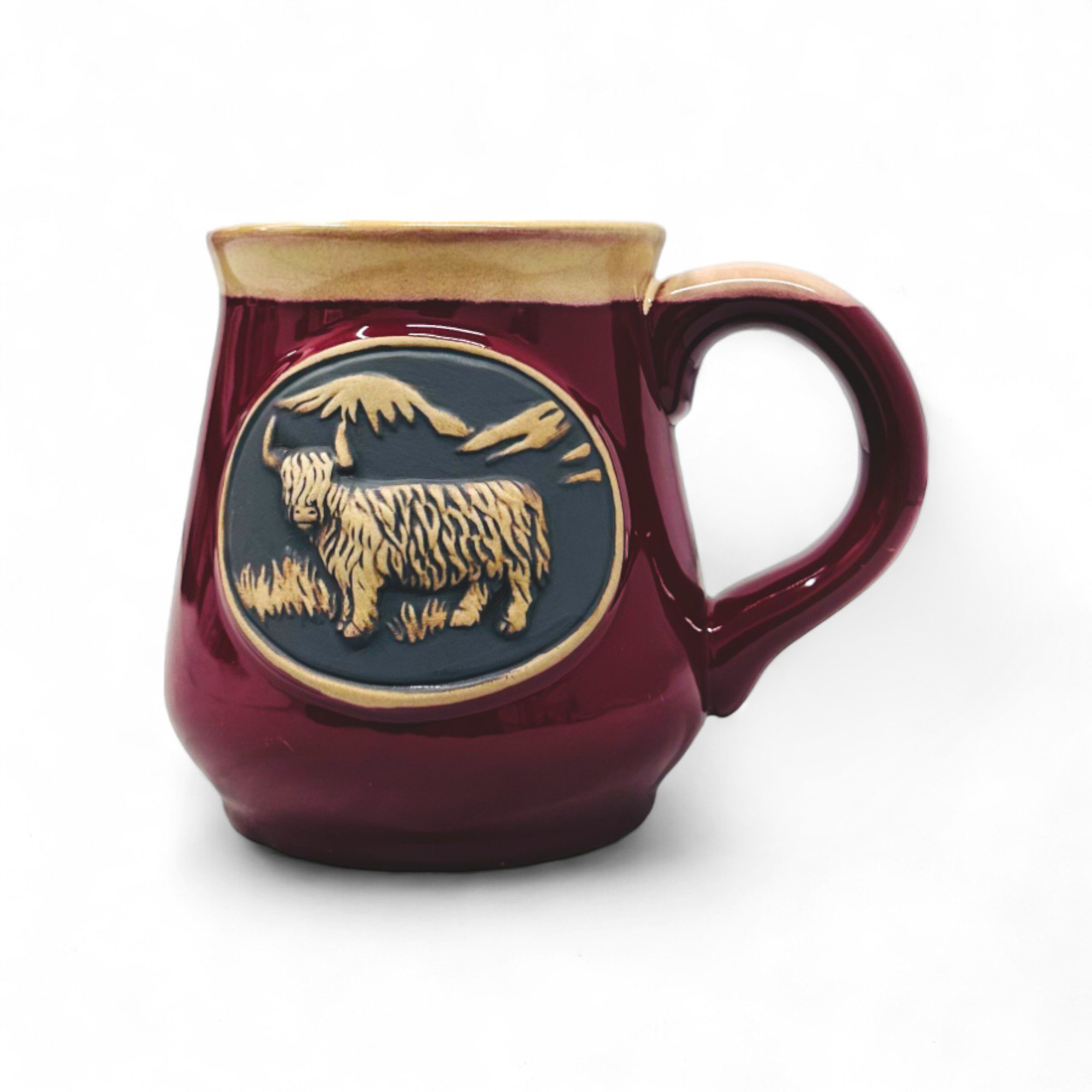 A red Scottish stoneware mug with a detailed Highland Cow design in the center.