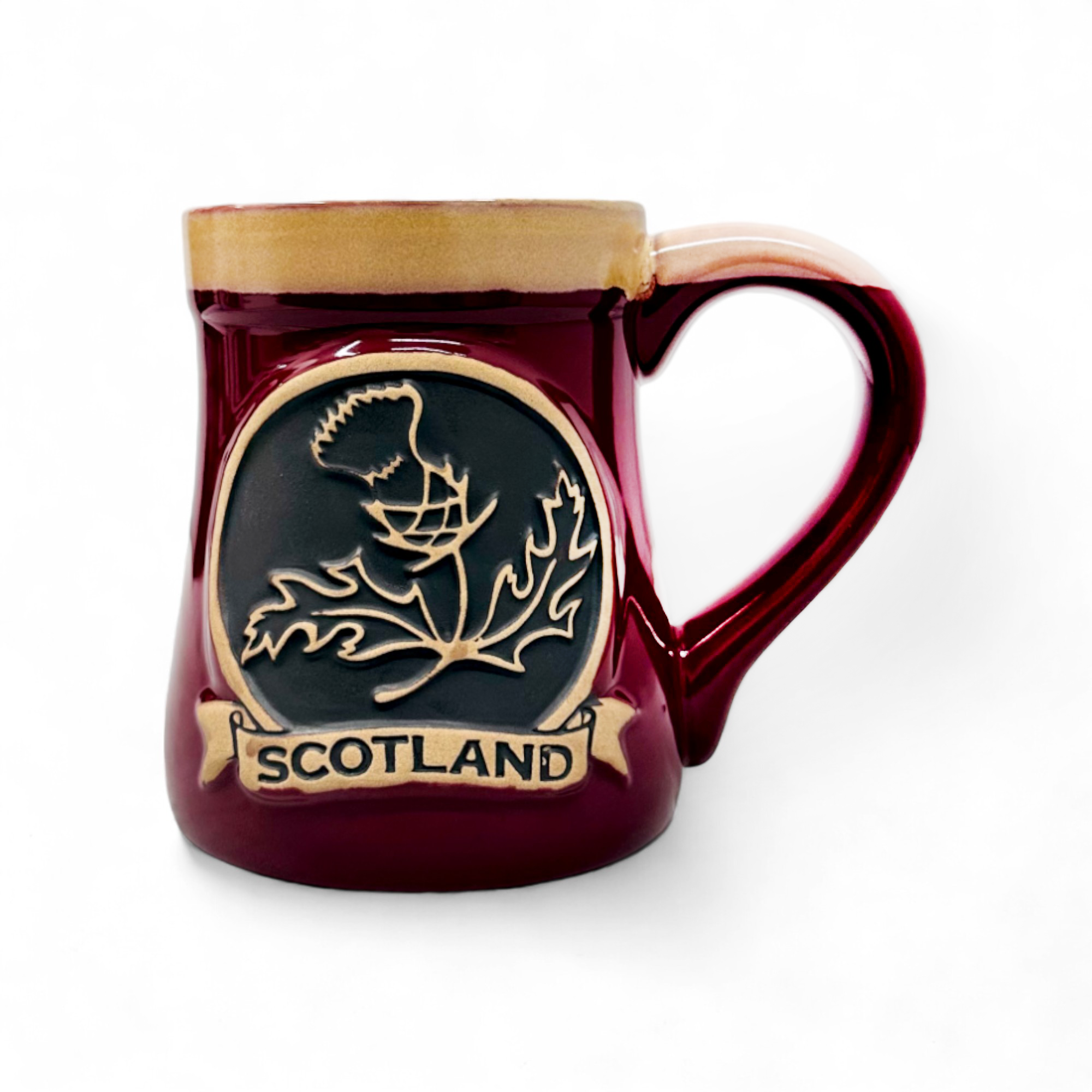 A red stoneware mug with a detailed thistle design and 'Scotland' text on it.